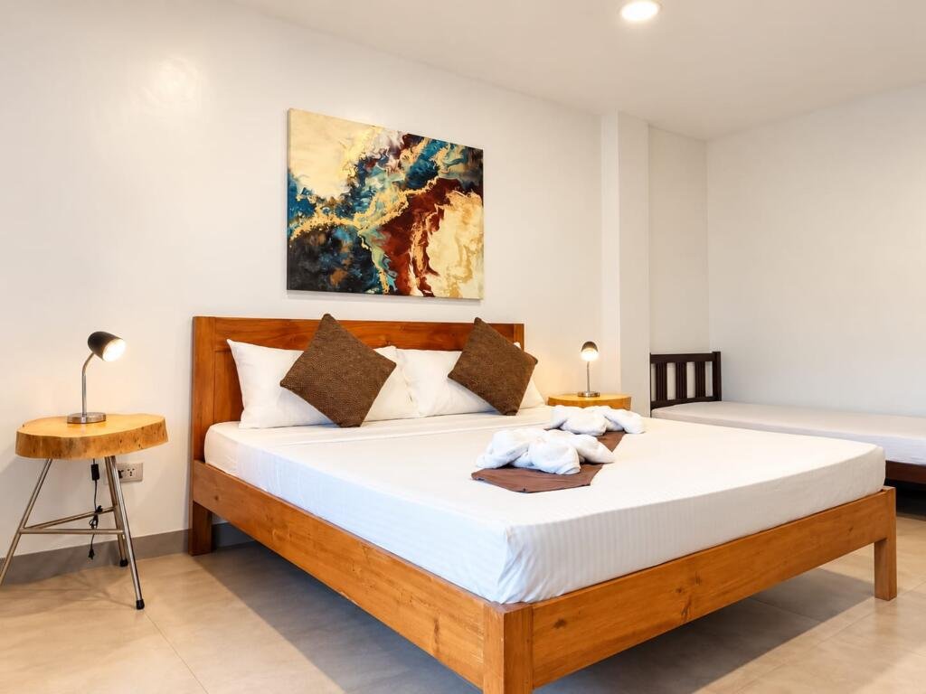 Hardwood king bed and bedside lamp in a Deluxe Seaview Room, Sunset Cove beach resort Romblon