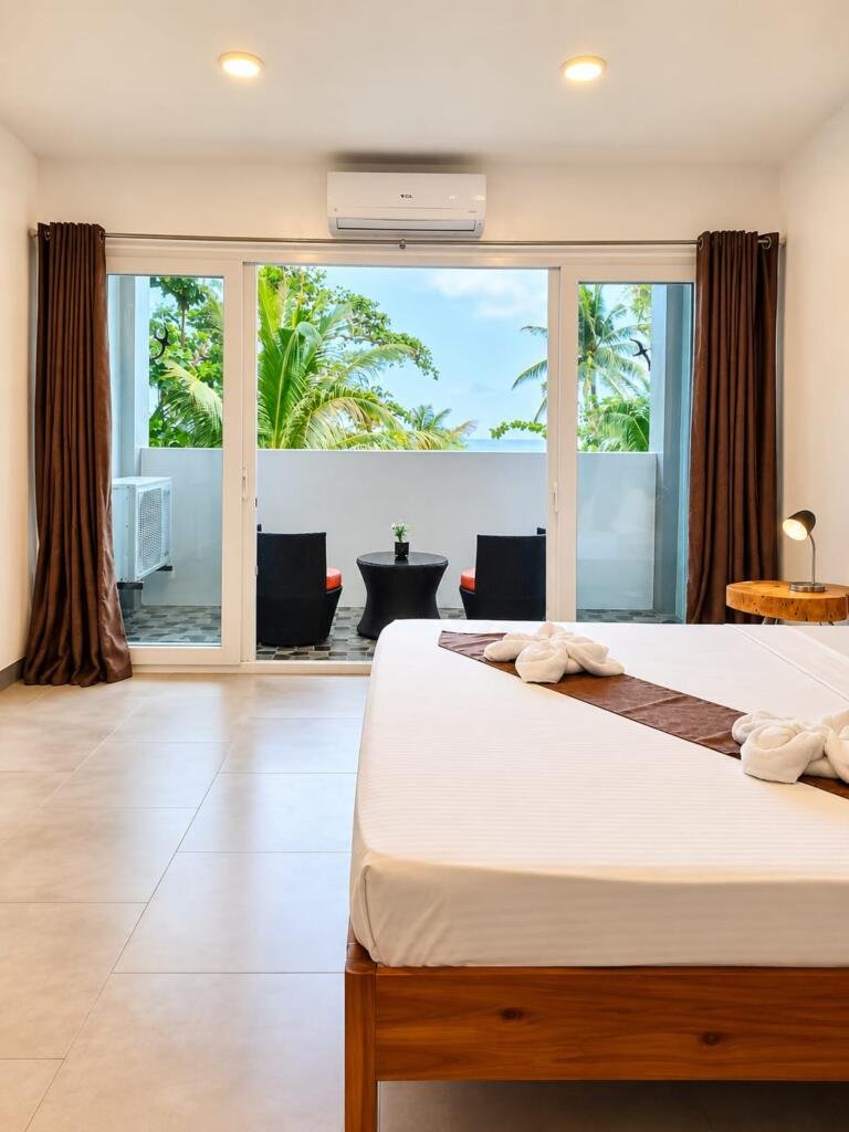 Deluxe Seaview Room bed facing sliding balcony doors and palms, Sunset Cove Romblon Philippines