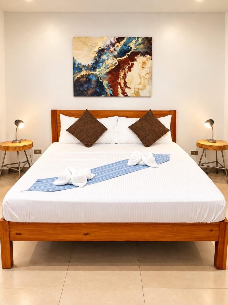 Suite Deluxe Seaview king bed with white linens and artwork, Sunset Cove beach resort Romblon